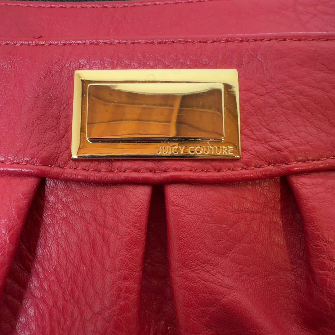 Red leather pleated clutch wristlet styled with black outfit, showing side profile and wristlet strap