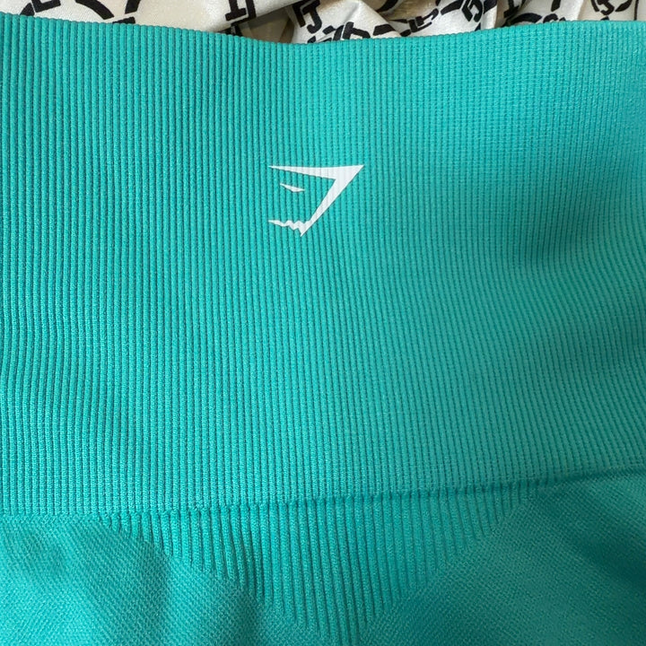 Side view of turquoise seamless cropped leggings showing textured mesh detailing and fitted silhouette