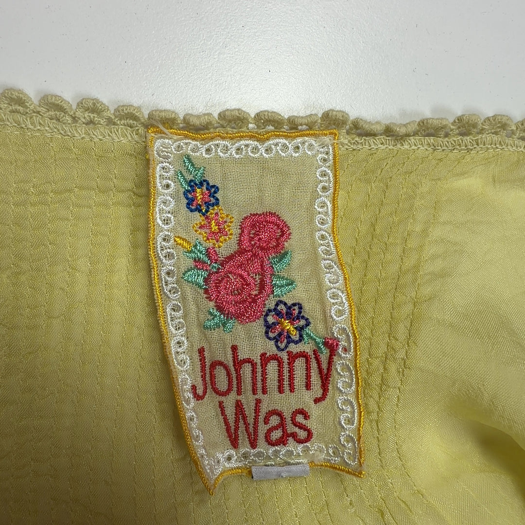 Tag view of pale yellow embroidered tunic top showing relaxed fit and cutout sleeve details