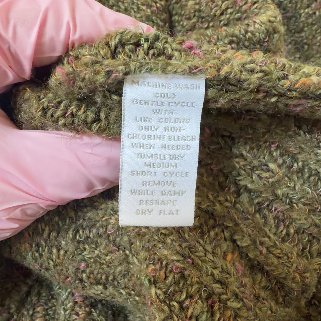 Tag view of olive green knit cardigan showing relaxed fit and ribbed hem detail