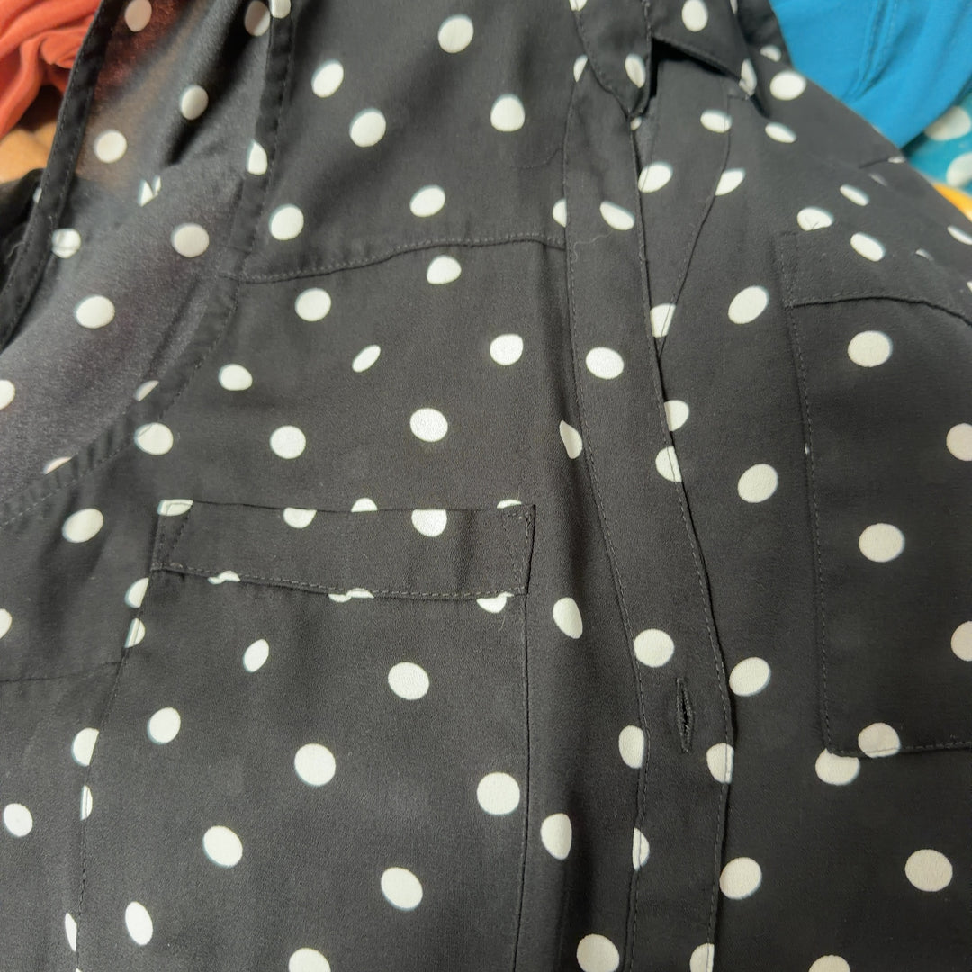 Black sleeveless button-up blouse with white polka dot pattern, back view