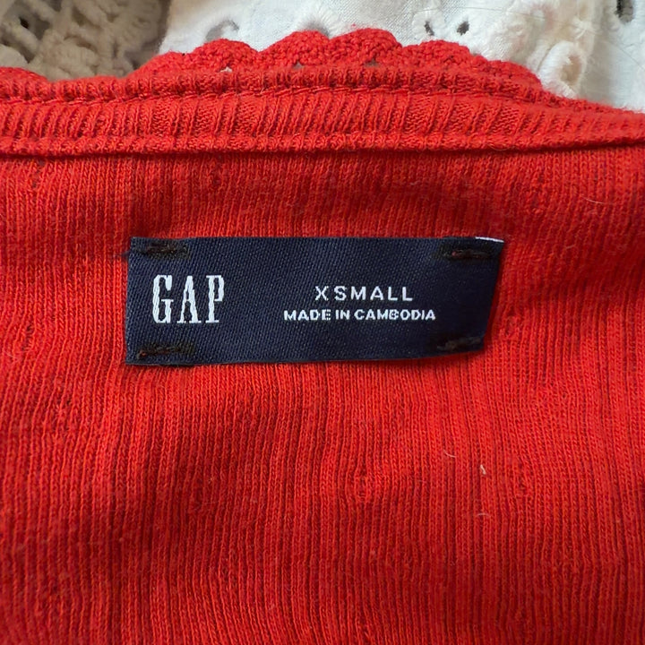 Tag view of red ribbed cotton crop cardigan showing fitted silhouette and cropped length