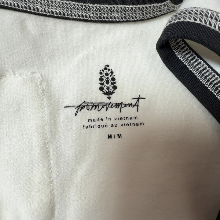 Tag view of cream tank top showing fitted silhouette and black button detailing