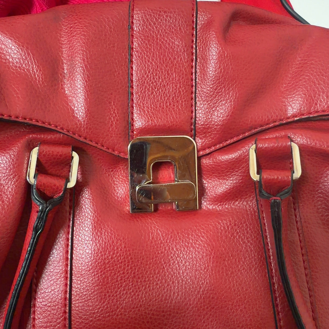 Tag view of red leather shoulder bag with dual shoulder straps worn by model