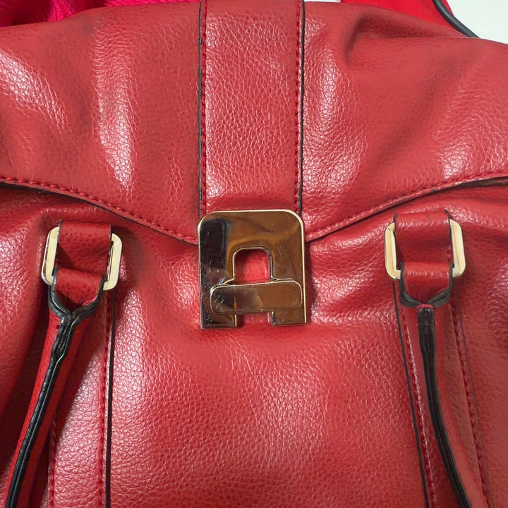 Tag view of red leather shoulder bag with dual shoulder straps worn by model