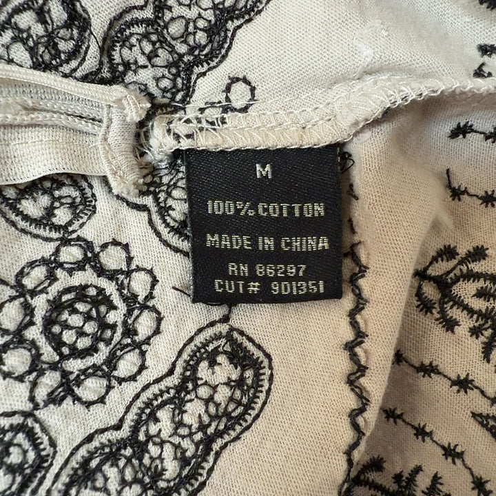 Tag view of cream embroidered cotton top showing empire waist and scalloped hem detail