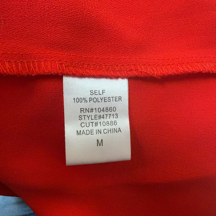 Red sleeveless button-up top with gold studded collar, back view on model