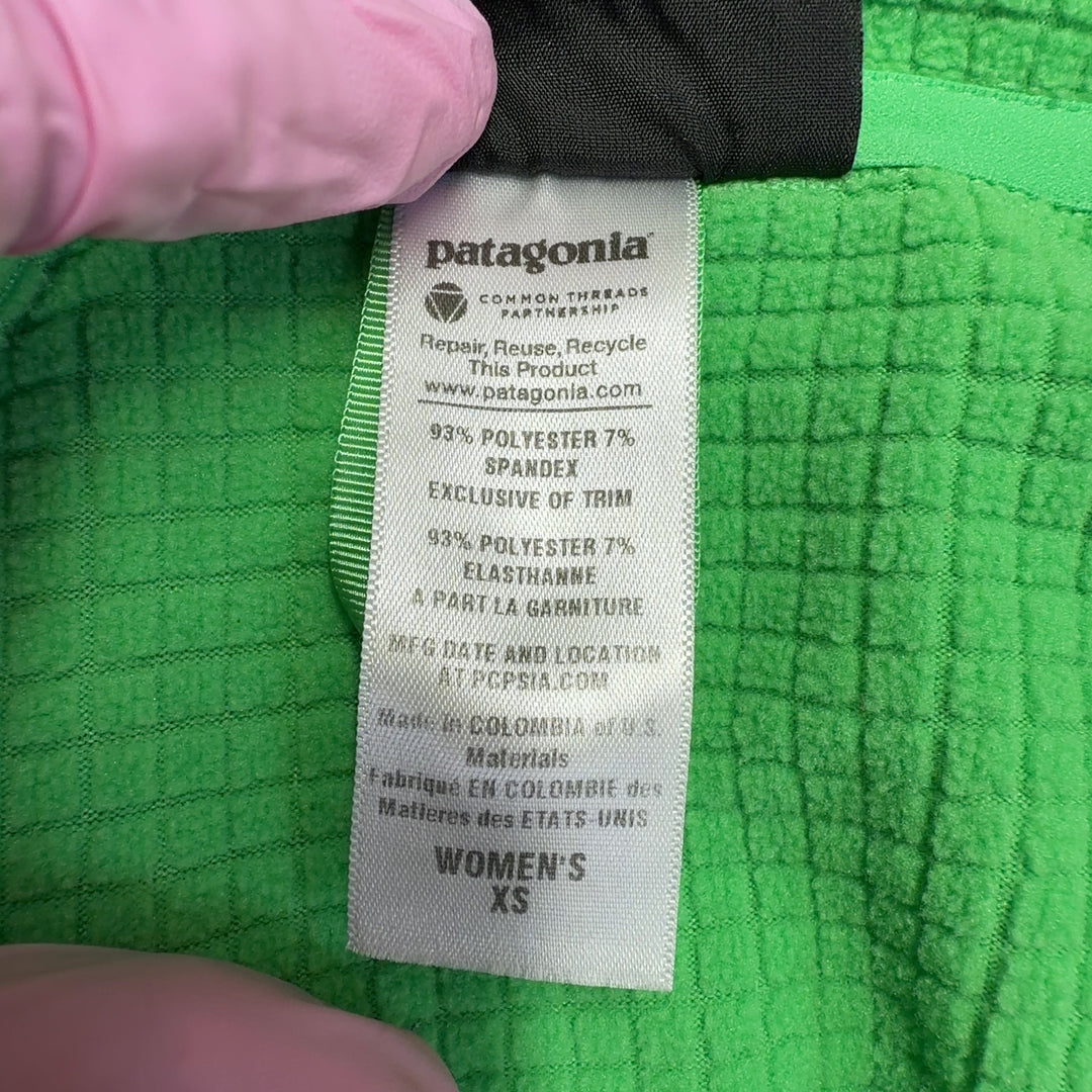 Green Patagonia quarter-zip long sleeve athletic top, back view on model wearing black leggings