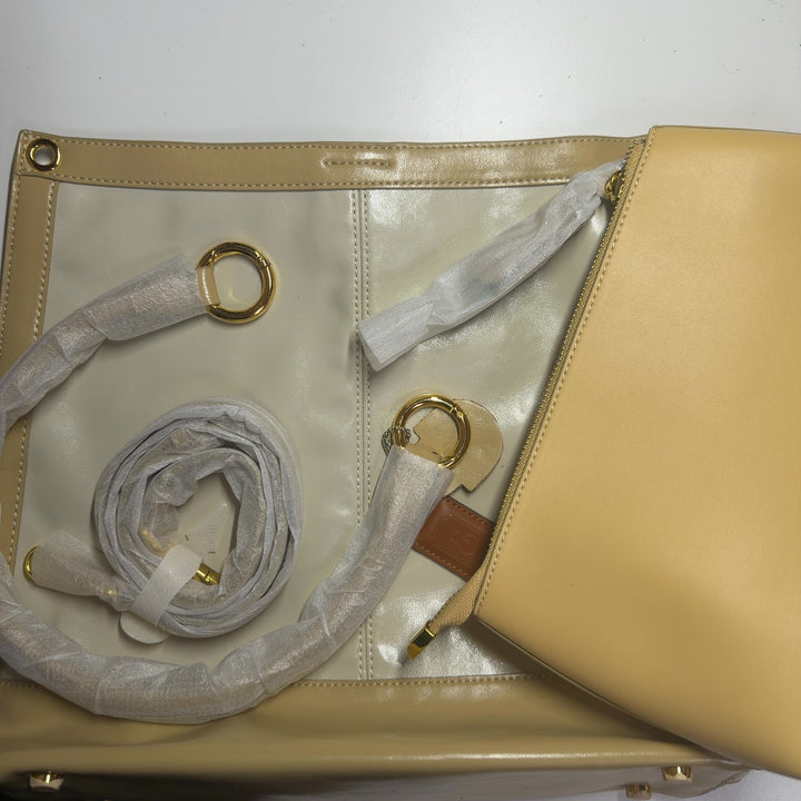 Tag view of SilkRoll gold leather crossbody bag worn as shoulder bag, displaying two-tone leather construction and polished hardware