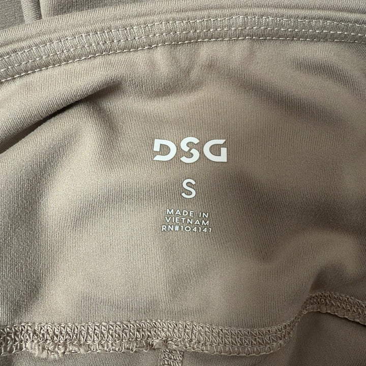 Woman wearing beige high-waist capri leggings with side pockets, back view showing fitted silhouette