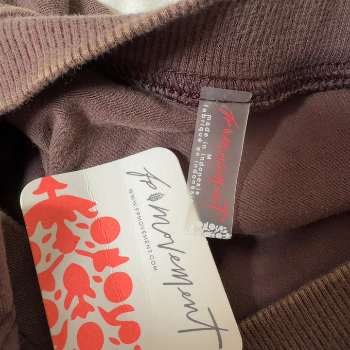 Tag view of brown twisted crop tank top showing draped design detail