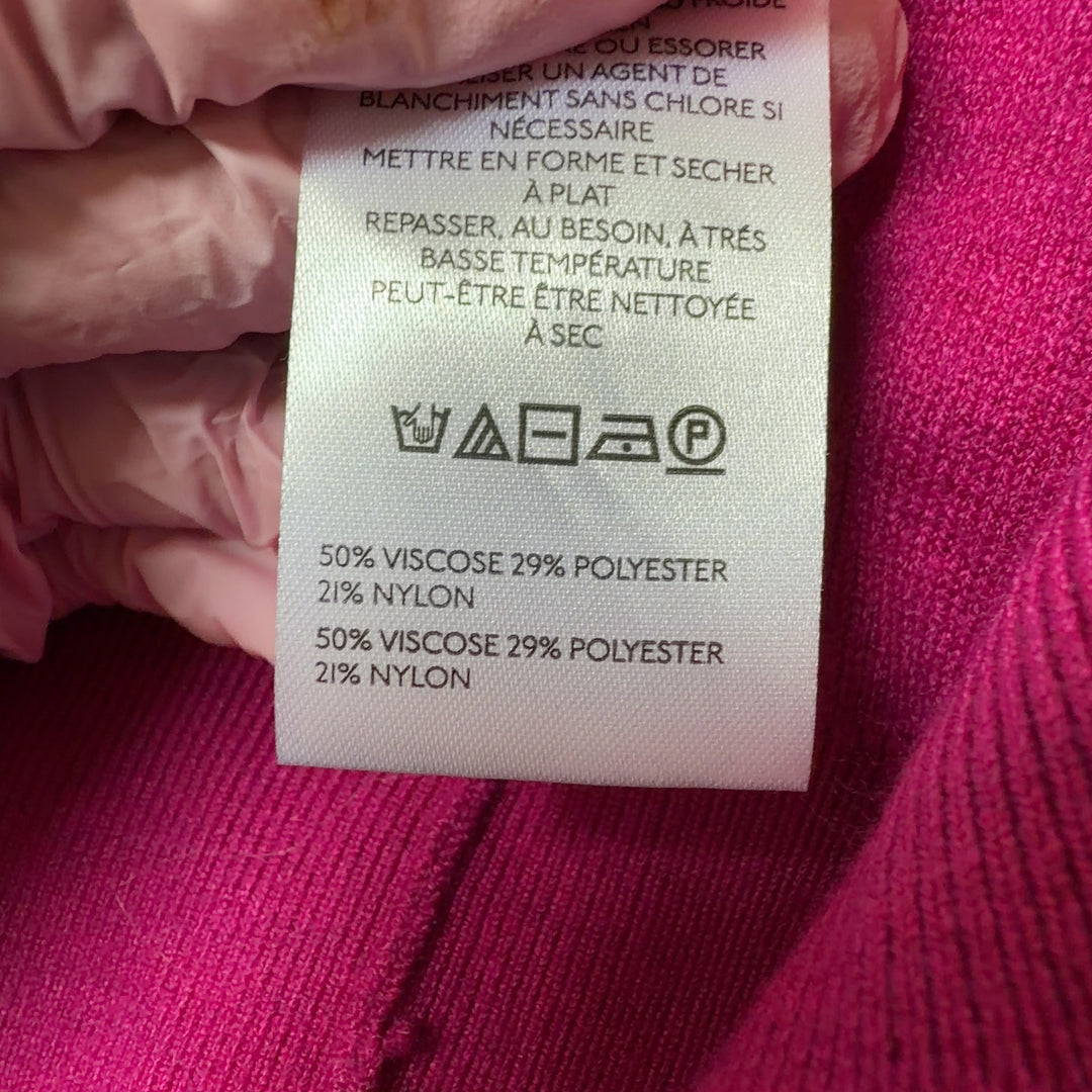 Tag view of pink knit vest showing button-front closure and relaxed fit silhouette