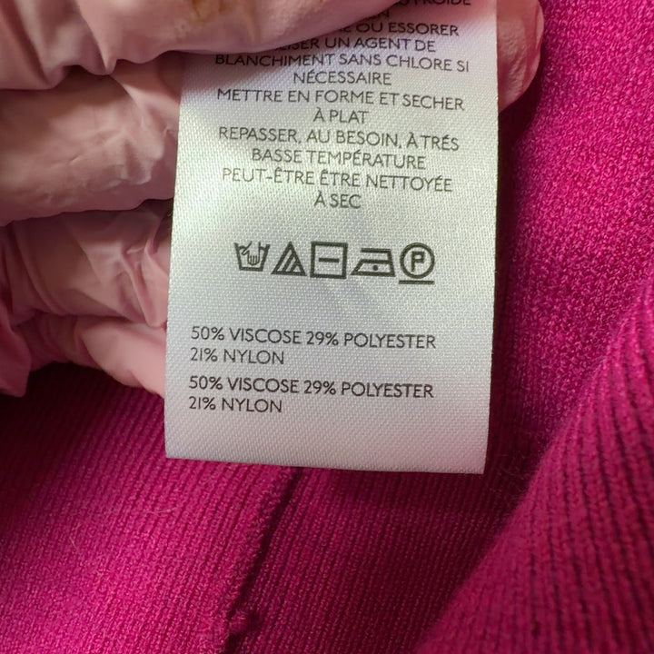 Tag view of pink knit vest showing button-front closure and relaxed fit silhouette