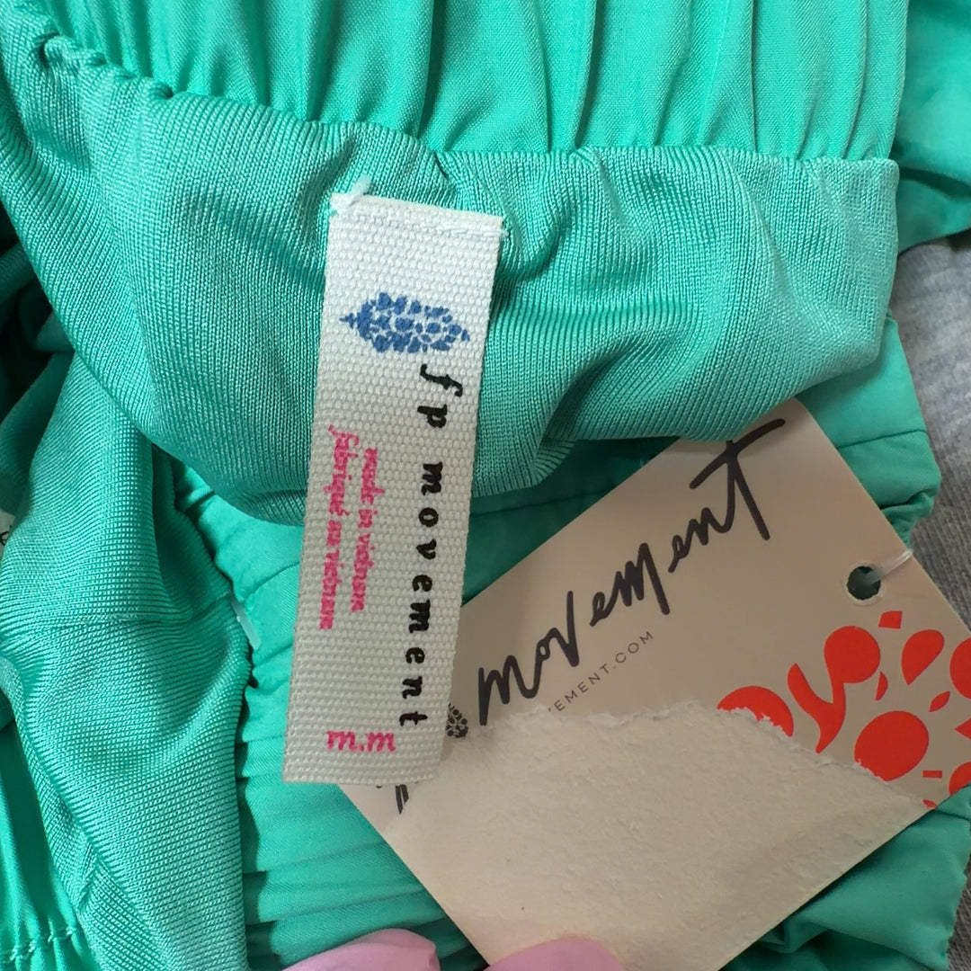 Mint green ruched athletic shorts with high waistband and flared hem, back view