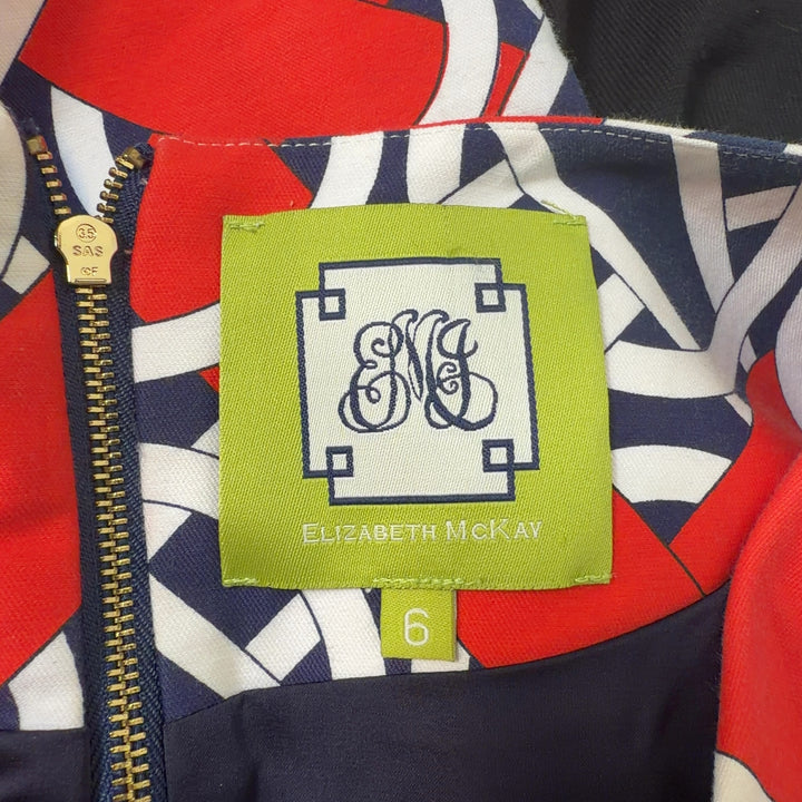 Red, navy, and white geometric print A-line dress with V-neckline and cap sleeves, back view
