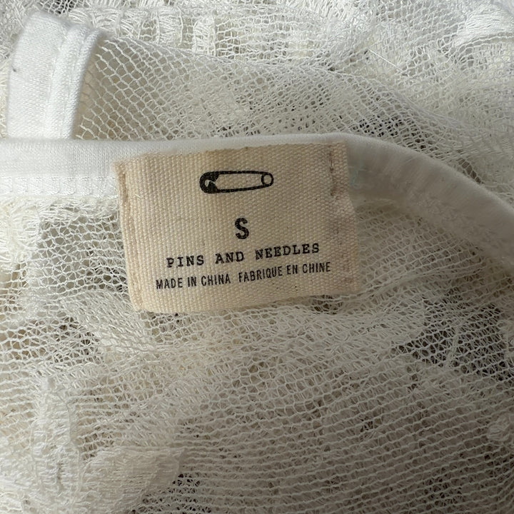 Tag view of cream lace tank top showing ornamental lace pattern and sage green underlay detail
