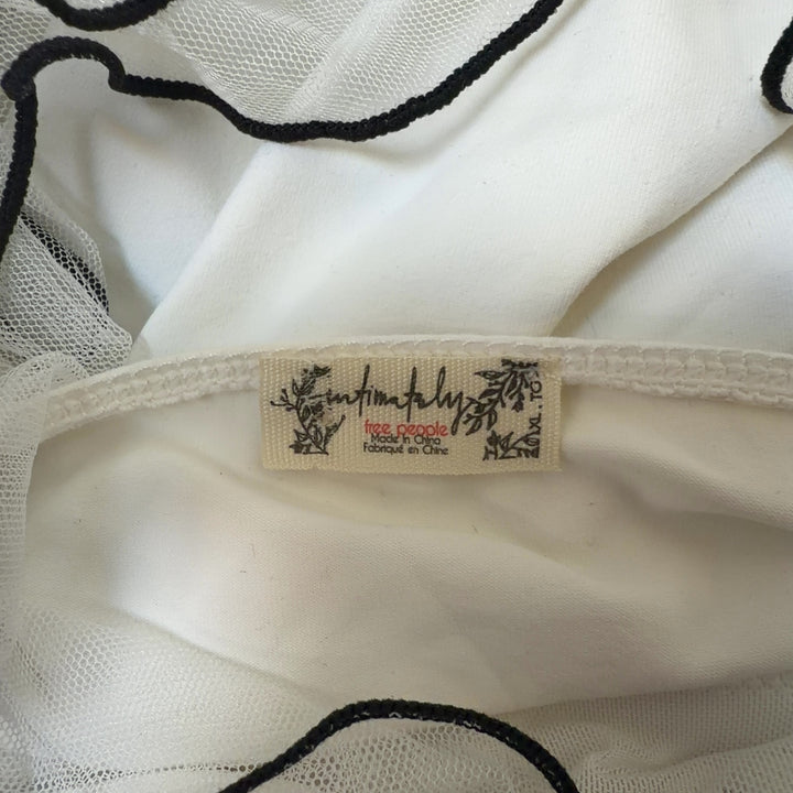 Tag view of cream ruffled crop top showing voluminous shoulder ruffles and cropped silhouette