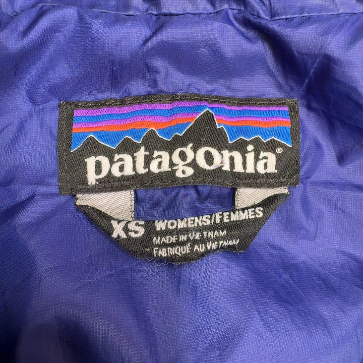 Tag view of turquoise quilted Patagonia puffer jacket with navy hood lining on woman