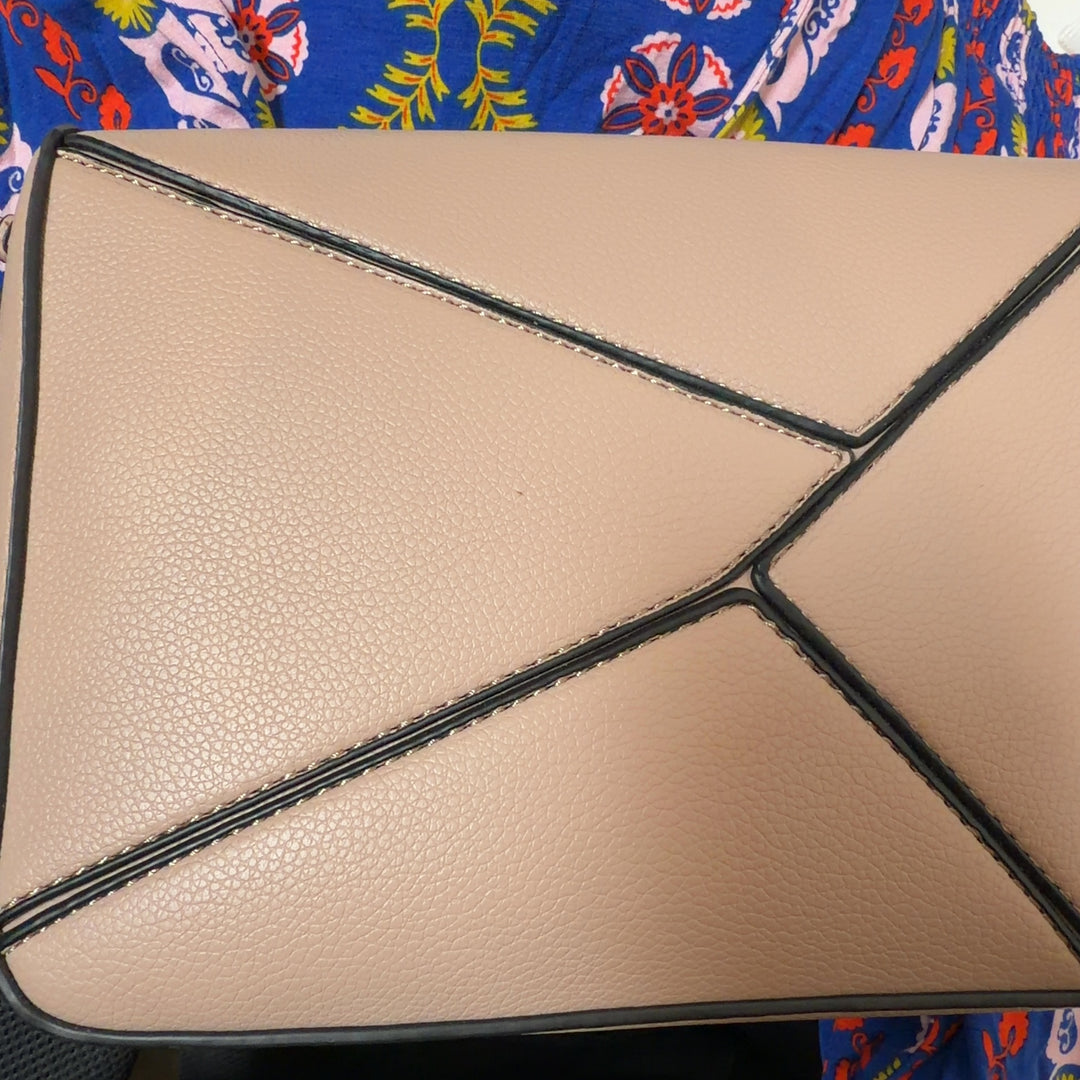Tag view of cream SilkRoll clutch bag worn as crossbody style with gold hardware details