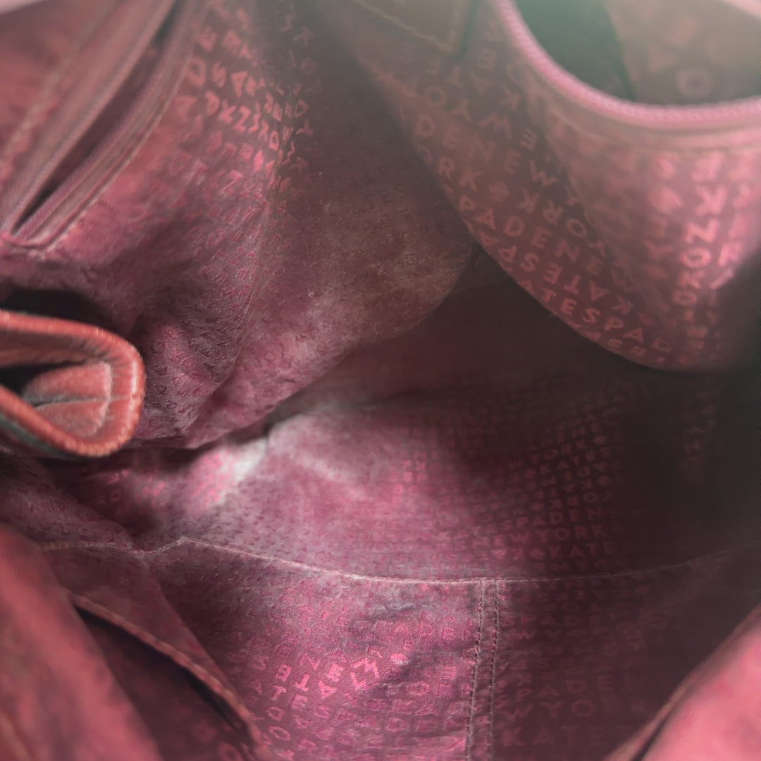 Burgundy leather Kate Spade backpack worn on shoulders, showing back view with adjustable straps and structured design