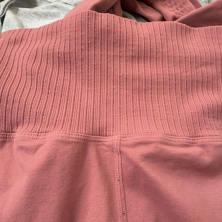 Tag view of pink high-waist ribbed leggings on model, showcasing smooth silhouette and premium fabric quality