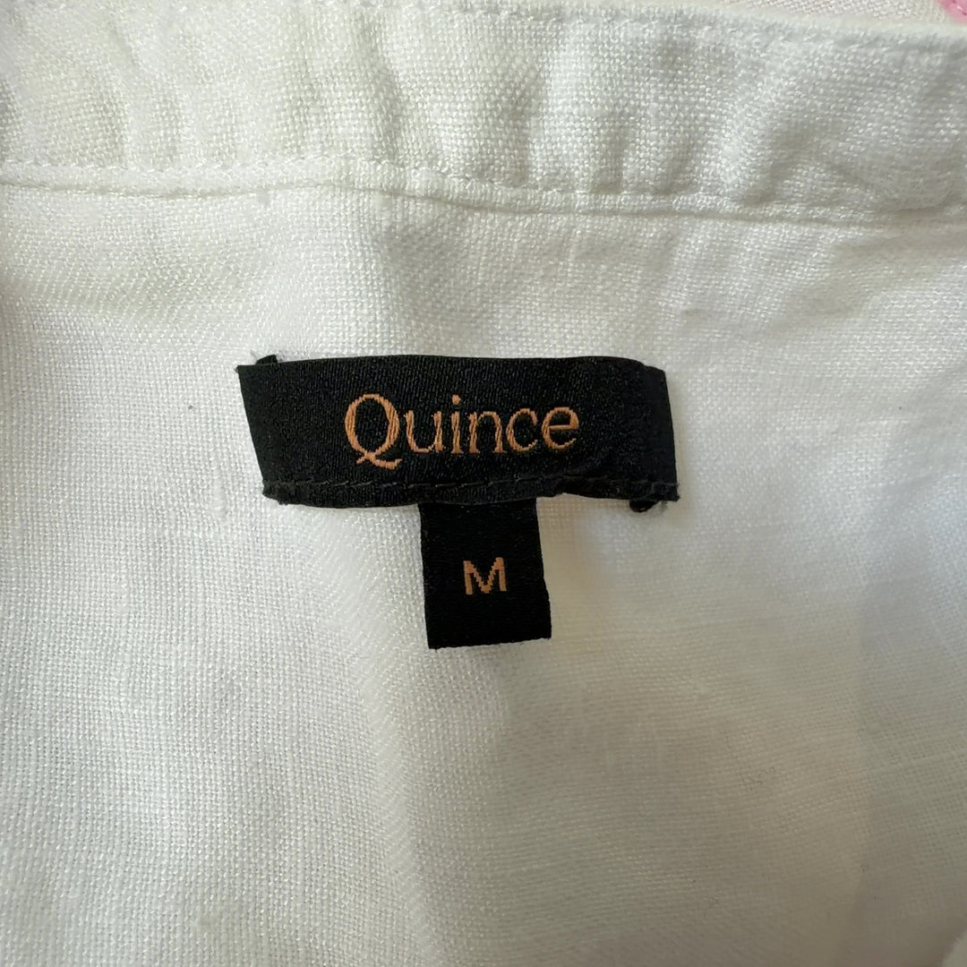 White linen sleeveless button-front dress with side pockets, back view