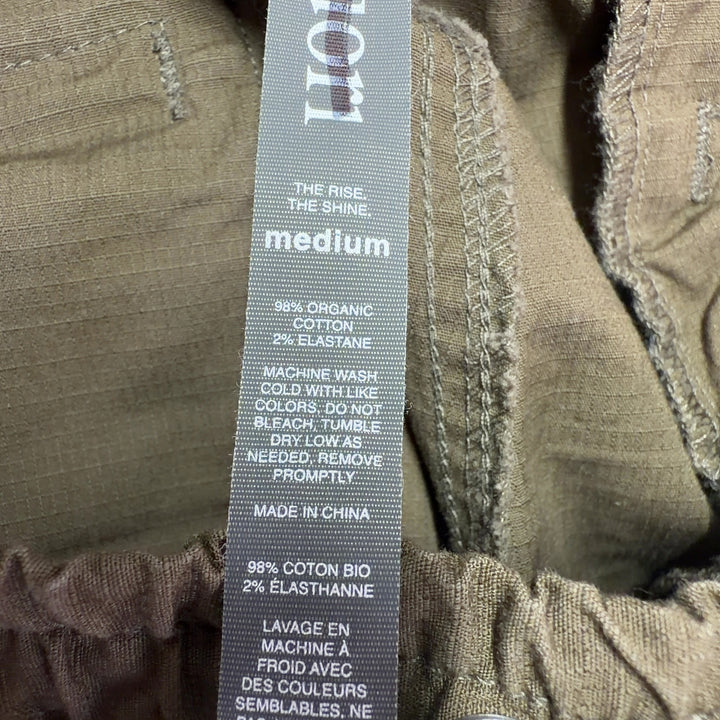 Tag view of brown cargo pants showing relaxed fit and rolled cuff detail