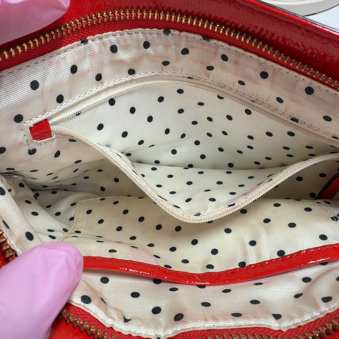 Kate Spade Red Patent Leather Crossbody Bag worn as crossbody on model showing back view and strap adjustment