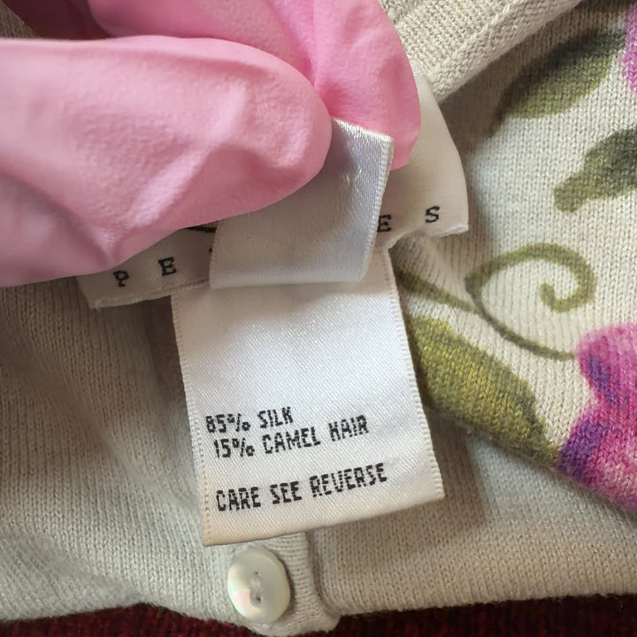 Tag view of cream floral cardigan showing full botanical print design and fitted silhouette