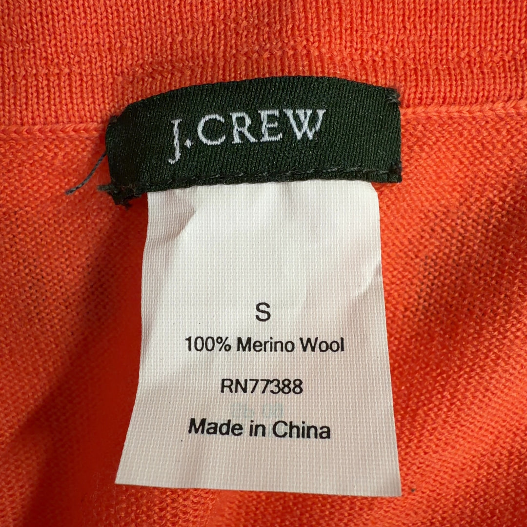 Tag view of orange merino wool cardigan showing relaxed fit and ribbed cuffs