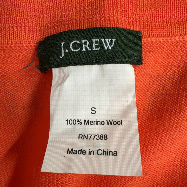 Tag view of orange merino wool cardigan showing relaxed fit and ribbed cuffs