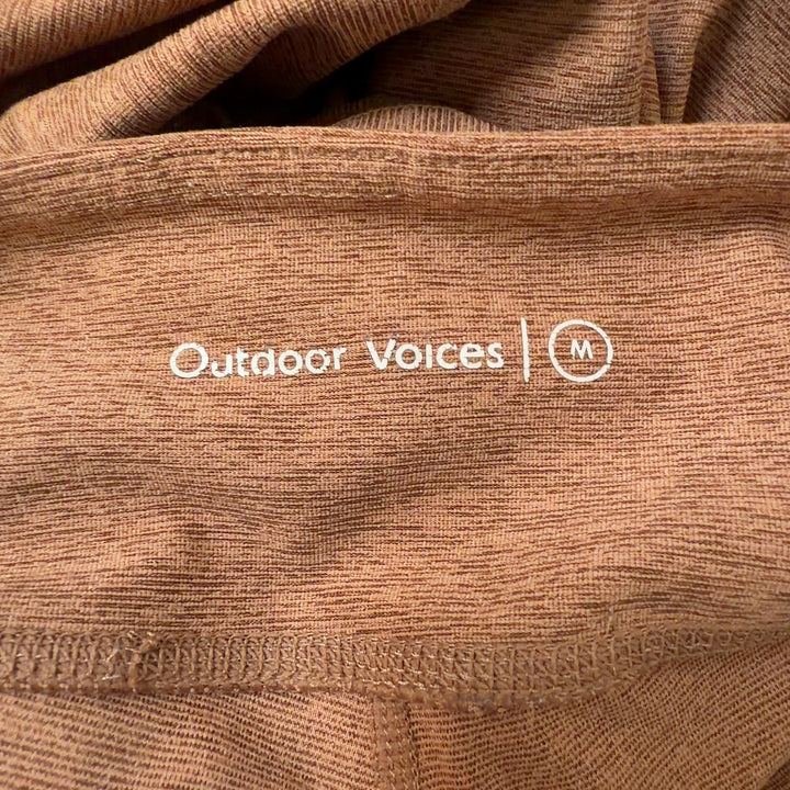 Tag view of orange heathered cropped leggings showing seamless construction and flattering silhouette