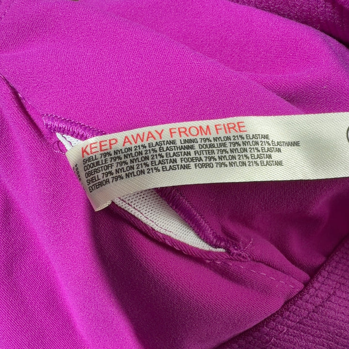 Woman wearing magenta sports bra with black leggings, back view showing crop top design