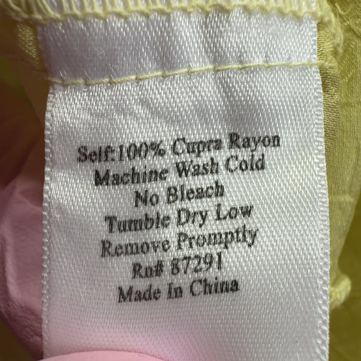 Tag view of pale yellow embroidered tunic top showing relaxed fit and cutout sleeve details