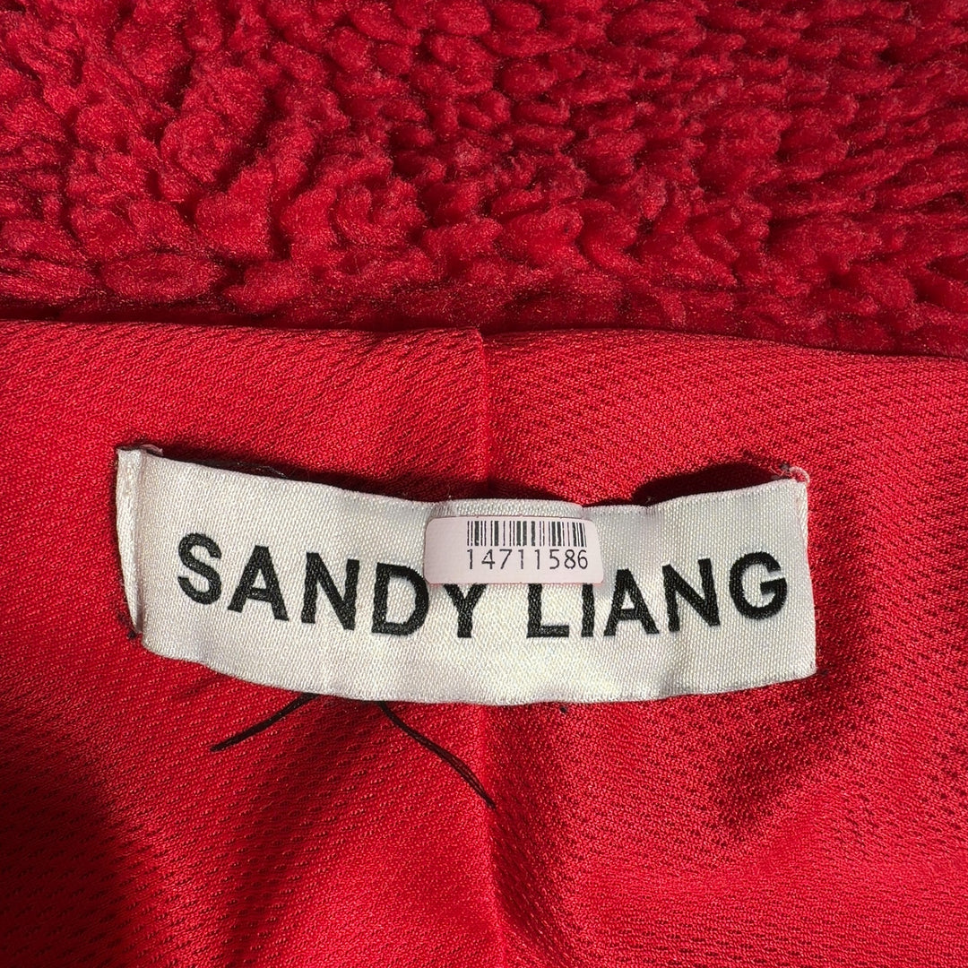 Tag view of red fuzzy jacket showing floral-printed trim detail and oversized silhouette