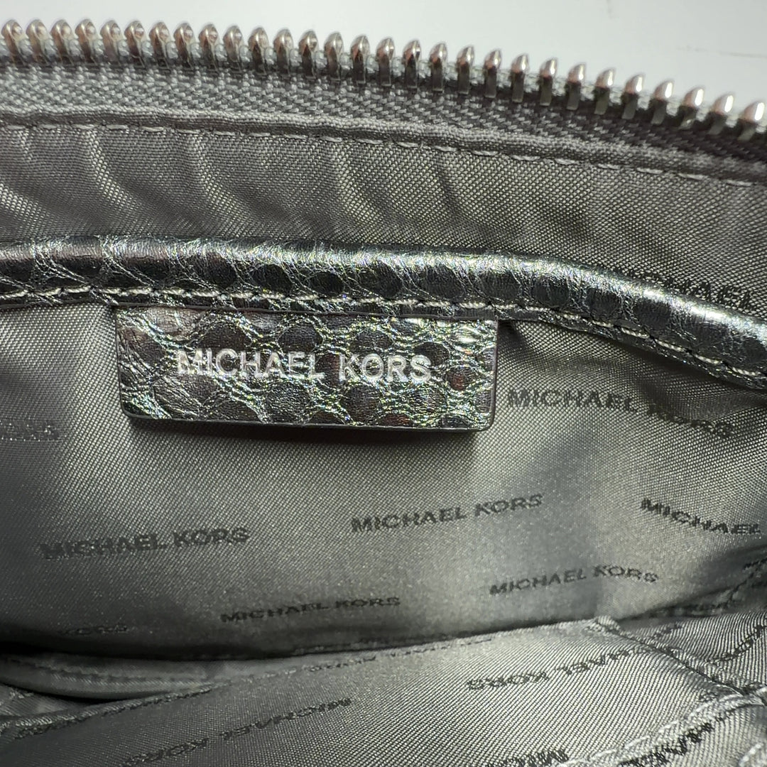 Silver metallic clutch worn as shoulder bag, displaying chain strap and quilted pattern detail