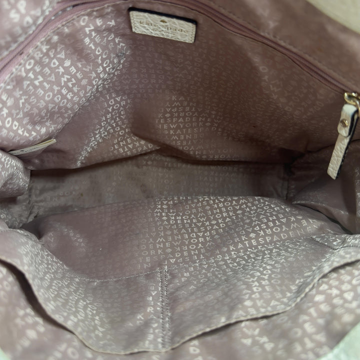 Tag view of cream Kate Spade perforated leather shoulder tote bag showing structured silhouette
