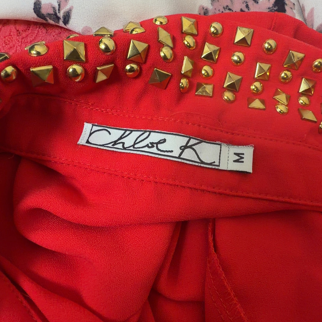 Red sleeveless button-up top with gold studded collar, back view on model
