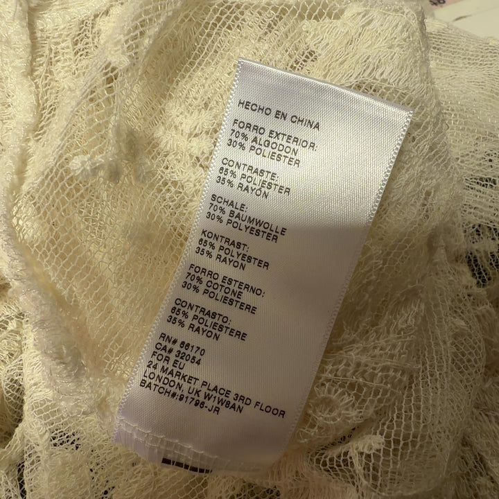 Tag view of cream lace tank top showing ornamental lace pattern and sage green underlay detail
