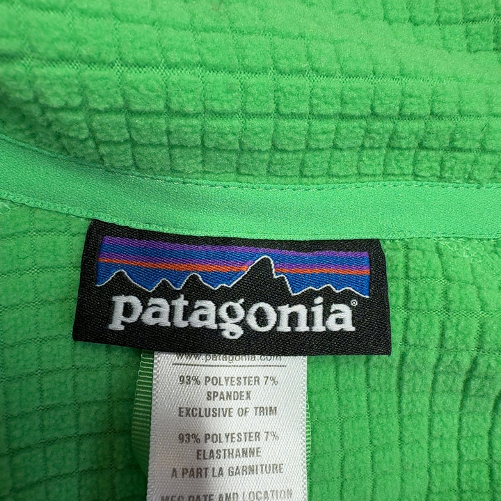 Green Patagonia quarter-zip long sleeve athletic top, back view on model wearing black leggings
