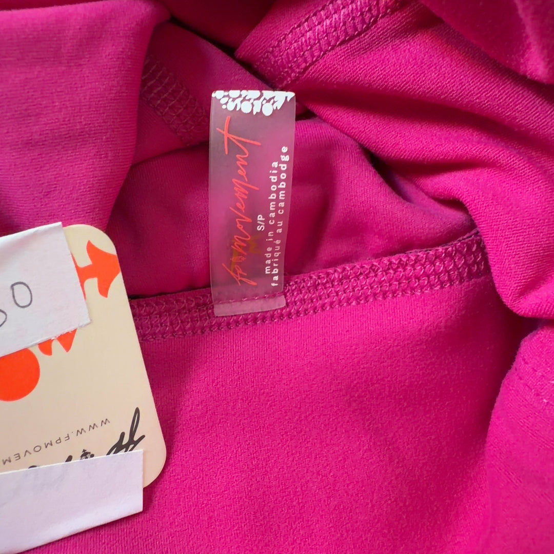Tag view of hot pink Free People jumpsuit showing sleeveless design and fitted waist with tapered leg detail