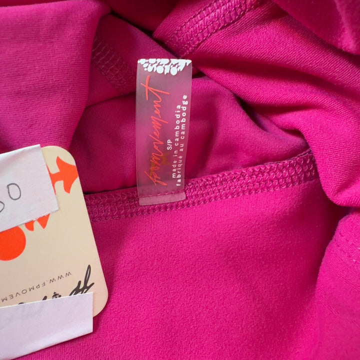 Tag view of hot pink Free People jumpsuit showing sleeveless design and fitted waist with tapered leg detail