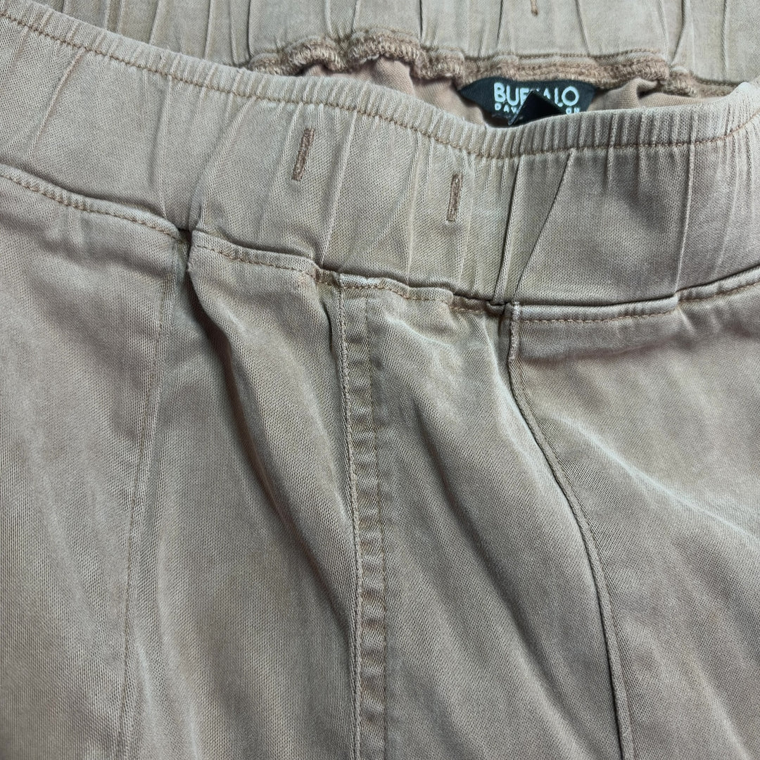 Beige cargo pants with rolled cuffs and side pockets, back view on model