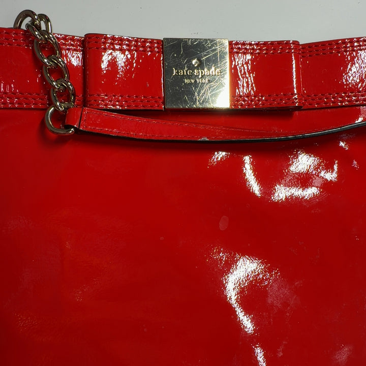 Kate Spade Red Patent Leather Crossbody Bag worn as crossbody on model showing back view and strap adjustment