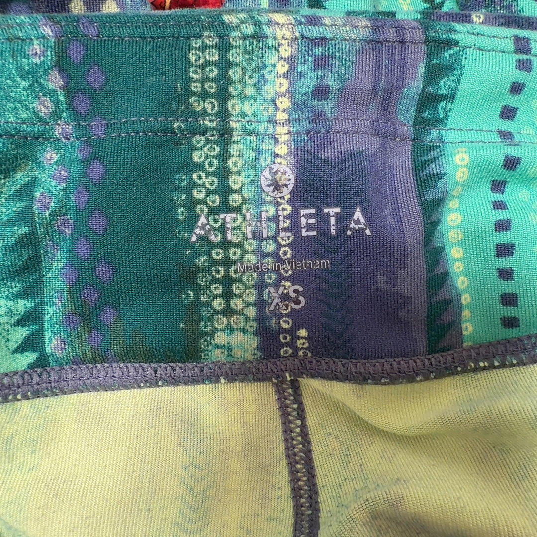 Tag view of green geometric print Athleta capri leggings showing flattering fit and calf-length cut