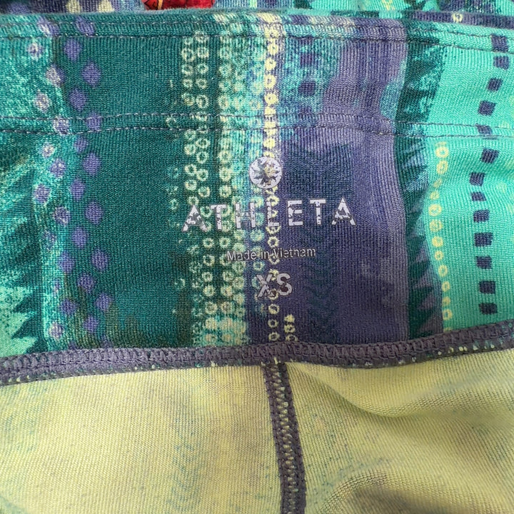 Tag view of green geometric print Athleta capri leggings showing flattering fit and calf-length cut