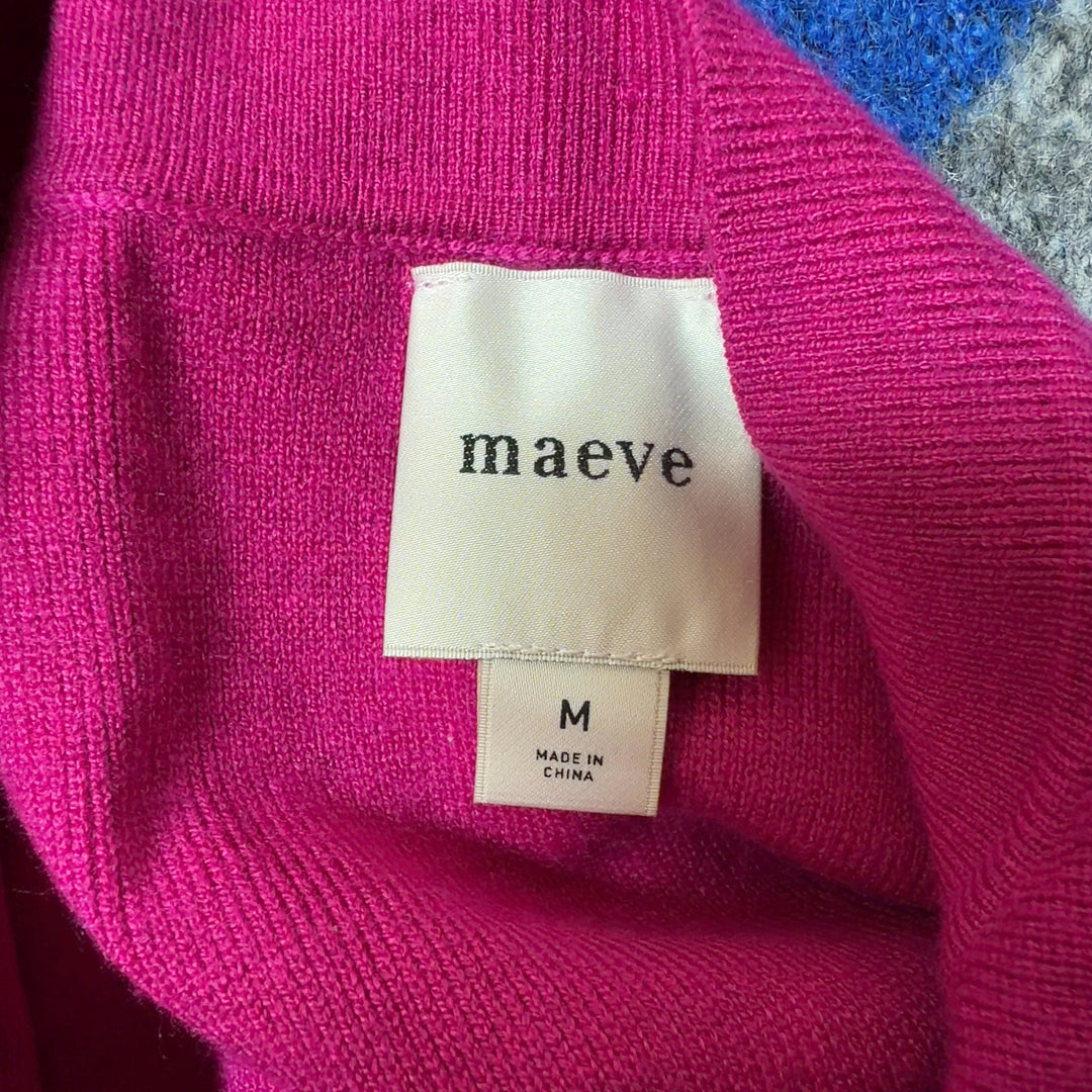 Tag view of pink knit vest showing button-front closure and relaxed fit silhouette