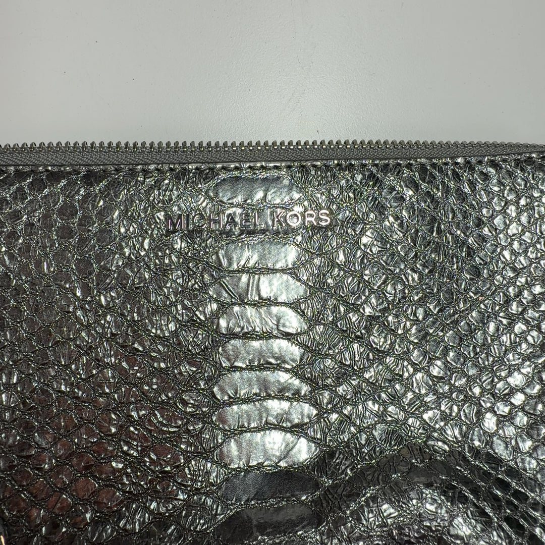 Silver metallic clutch worn as shoulder bag, displaying chain strap and quilted pattern detail