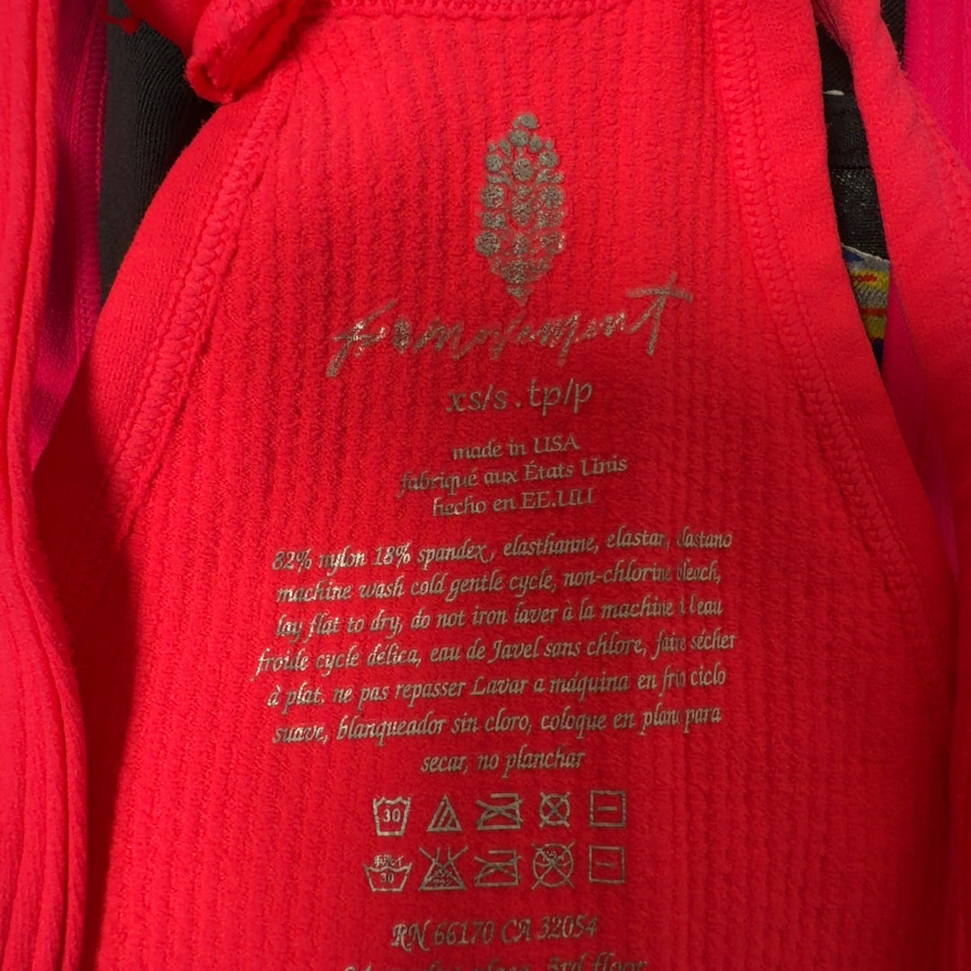Woman wearing pink ribbed crop tank top with racerback design and black leggings, back view