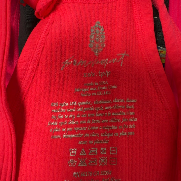 Woman wearing pink ribbed crop tank top with racerback design and black leggings, back view